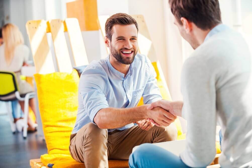 How does Lottoland work? Two men smiling and shaking hands.